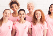 Breast Cancer. Ladies From Oncology Support Group Smiling To Camera Wearing T-Shirts With Pink Ribbon On White Background. Panorama